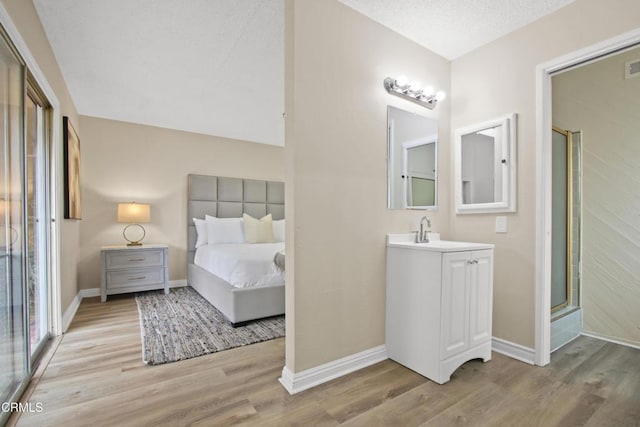 bedroom featuring light wood-style flooring, baseboards, and a sink