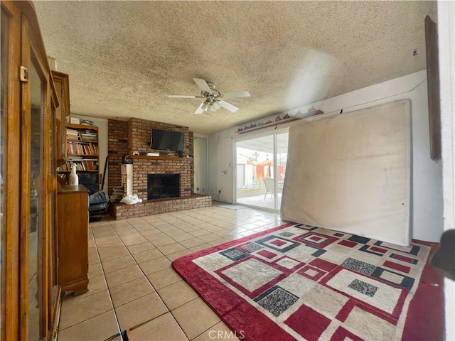 unfurnished living room with a ceiling fan, light tile patterned floors, a brick fireplace, and a textured ceiling