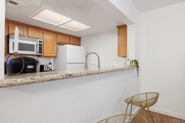 15048 Avenida Venusto Unit 255, San Diego, CA 92128 - kitchen with freestanding refrigerator, a sink, light stone countertops, wood finished floors, and brown cabinetry