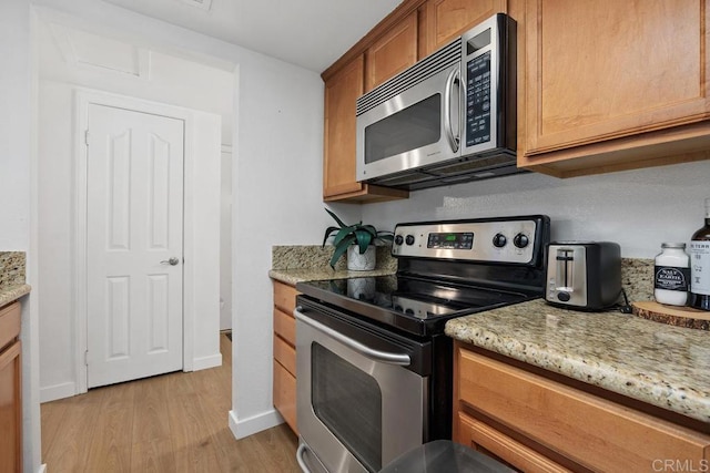 15048 Avenida Venusto Unit 255, San Diego, CA 92128 - kitchen featuring stainless steel appliances, light wood finished floors, light stone countertops, and baseboards