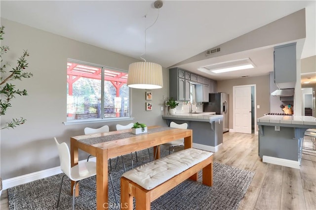 45792 Sutton Dr, Oakhurst, CA 93644 - dining area with light wood-style floors, baseboards, and vaulted ceiling