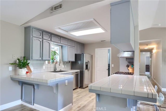 45792 Sutton Dr, Oakhurst, CA 93644 - kitchen featuring a sink, tile countertops, a peninsula, vaulted ceiling, and appliances with stainless steel finishes