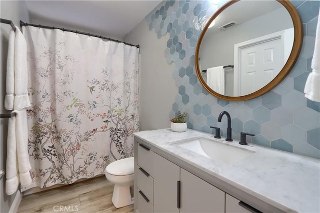 45792 Sutton Dr, Oakhurst, CA 93644 - bathroom featuring wood finished floors, decorative backsplash, vanity, toilet, and curtained shower