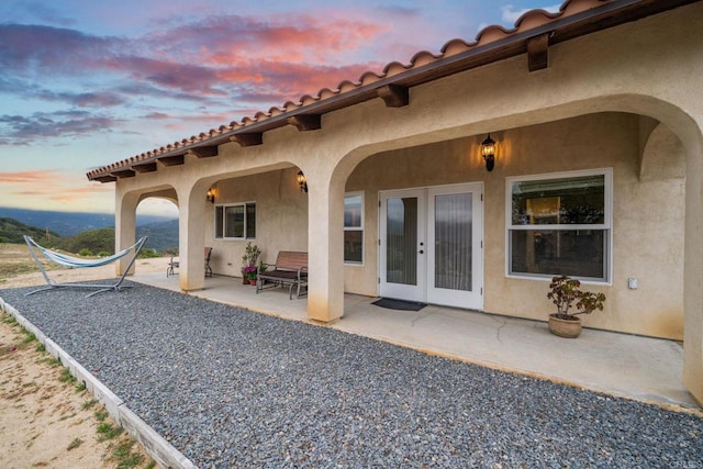 2389 Eric Rd, Fallbrook, CA 92028 - back of property at dusk with a patio, stucco siding, french doors, and a tiled roof