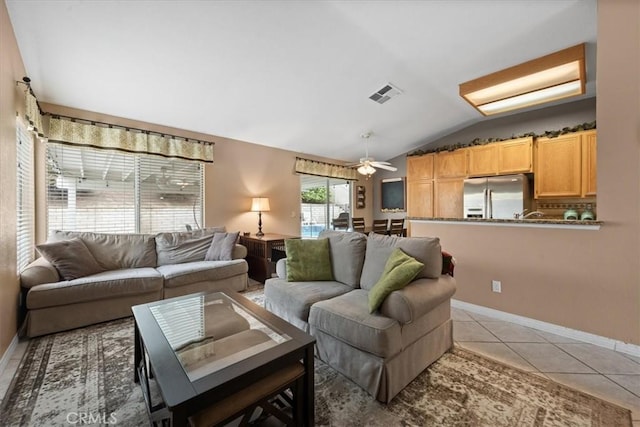 living area featuring vaulted ceiling, light tile patterned floors, baseboards, and ceiling fan