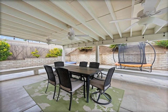 view of patio with ceiling fan, fence, a trampoline, and outdoor dining area