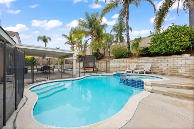 view of swimming pool with a patio, a pool with connected hot tub, and a fenced backyard