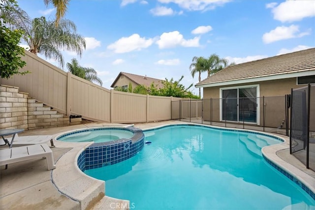 view of pool with fence and a pool with connected hot tub