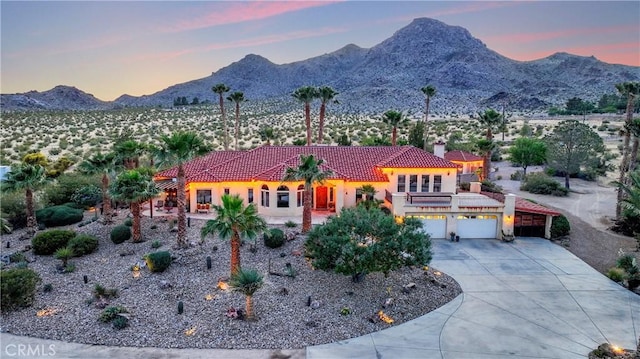 31024 Rabbit Springs Rd, Lucerne Valley, CA 92356 - view of front facade featuring a tiled roof, concrete driveway, a mountain view, stucco siding, and a garage
