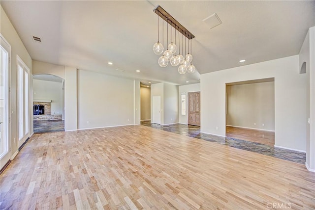 43922 Carentan Dr, Temecula, CA 92592 - empty room featuring wood finished floors, recessed lighting, arched walkways, and a fireplace with raised hearth