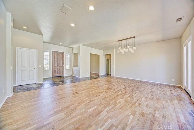 43922 Carentan Dr, Temecula, CA 92592 - unfurnished living room with wood finished floors, healthy amount of natural light, recessed lighting, arched walkways, and a chandelier