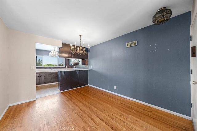 unfurnished dining area featuring a chandelier, wood finished floors, and baseboards