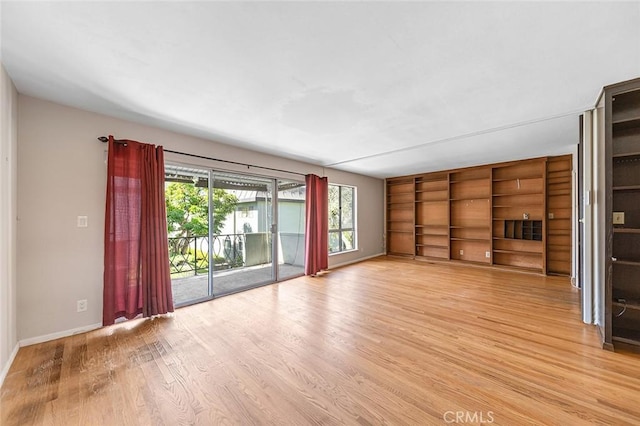 unfurnished living room featuring baseboards, light wood-type flooring, and built in features