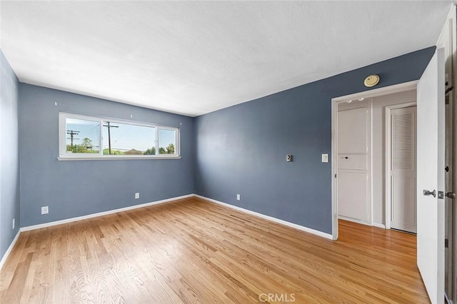 empty room with light wood finished floors and baseboards