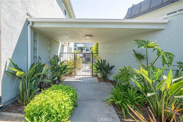 doorway to property featuring stucco siding, a gate, and fence
