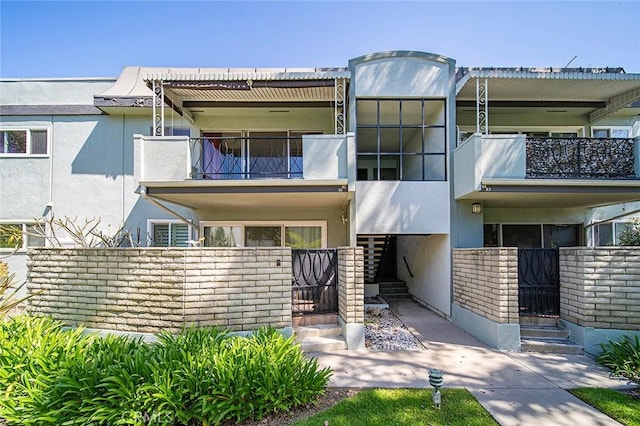 view of front of home featuring stucco siding, a balcony, and stairs