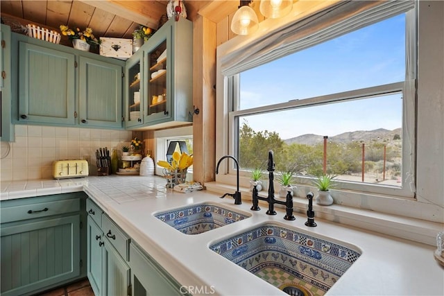 51609 Oregon Trl, Morongo Valley, CA 92256 - kitchen featuring green cabinetry, a sink, backsplash, a mountain view, and glass insert cabinets