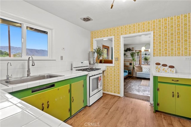 51609 Oregon Trl, Morongo Valley, CA 92256 - kitchen with gas range gas stove, wallpapered walls, a sink, tile counters, and light wood finished floors