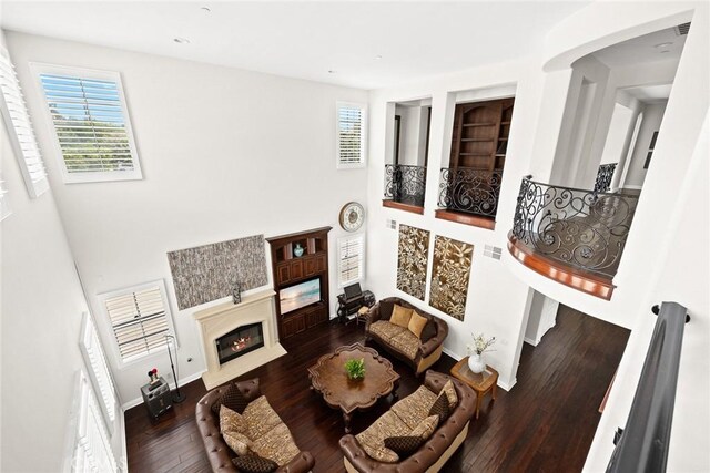 4448 St Cloud, Claremont, CA 91711 - living area featuring a glass covered fireplace, hardwood / wood-style flooring, built in shelves, a towering ceiling, and baseboards