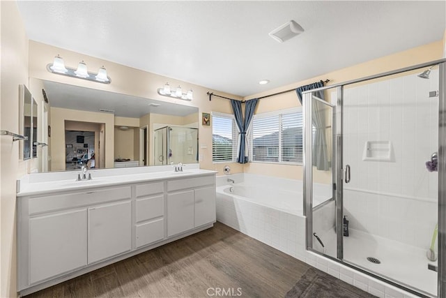 ensuite bathroom featuring a garden tub, a stall shower, double vanity, and wood finished floors