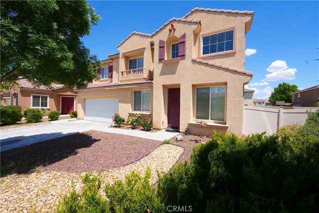 mediterranean / spanish house featuring stucco siding, a tile roof, concrete driveway, fence, and a garage