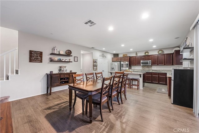 dining room with light wood finished floors, stairs, and recessed lighting