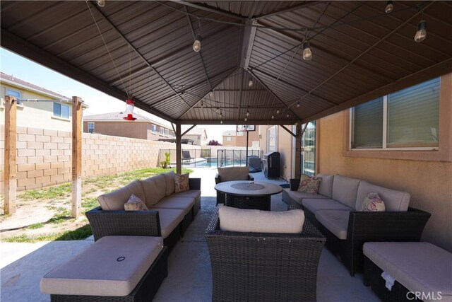 view of patio / terrace with an outdoor living space with a fire pit, a fenced backyard, and a gazebo