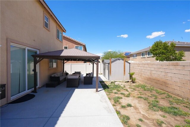 fenced backyard featuring outdoor lounge area, a patio, a shed, a gazebo, and an outbuilding