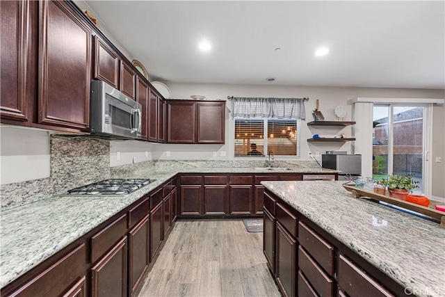 kitchen featuring appliances with stainless steel finishes, a sink, light stone counters, light wood-style flooring, and recessed lighting