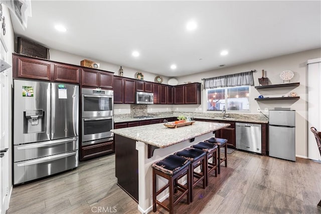 kitchen featuring stainless steel appliances, a center island, light wood finished floors, a breakfast bar, and recessed lighting