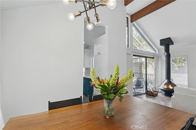 dining room featuring high vaulted ceiling, a wood stove, beam ceiling, and a chandelier