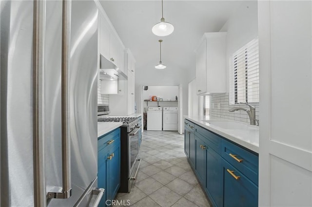 kitchen featuring stainless steel appliances, blue cabinetry, independent washer and dryer, a sink, and under cabinet range hood