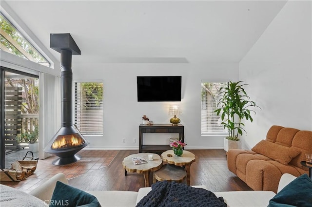 living area featuring a wood stove, wood-type flooring, and baseboards
