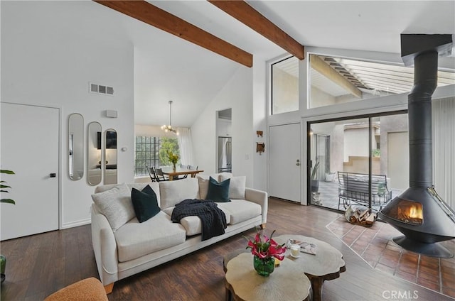 living room featuring beam ceiling, a wood stove, high vaulted ceiling, wood finished floors, and a chandelier