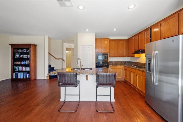 kitchen featuring appliances with stainless steel finishes, a sink, dark wood-style flooring, a center island with sink, and recessed lighting