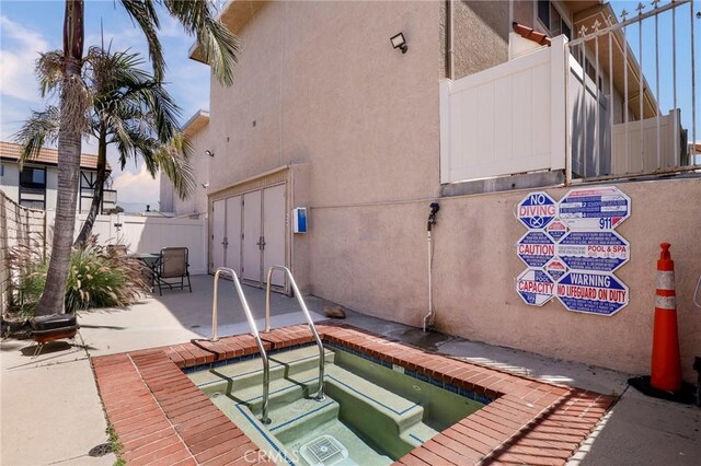 view of swimming pool with a community hot tub, fence, and a patio