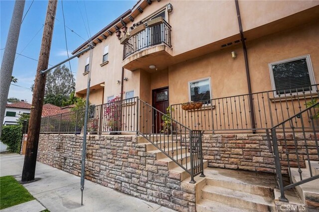 14702 Magnolia Blvd Unit 104, Sherman Oaks, CA 91403 - view of exterior entry with a balcony, stucco siding, and fence