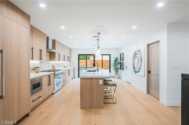 kitchen with high end range, wall chimney exhaust hood, a sink, modern cabinets, and light wood-style flooring