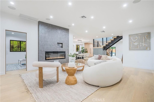 living room featuring light wood-type flooring, stairway, a fireplace, baseboards, and recessed lighting