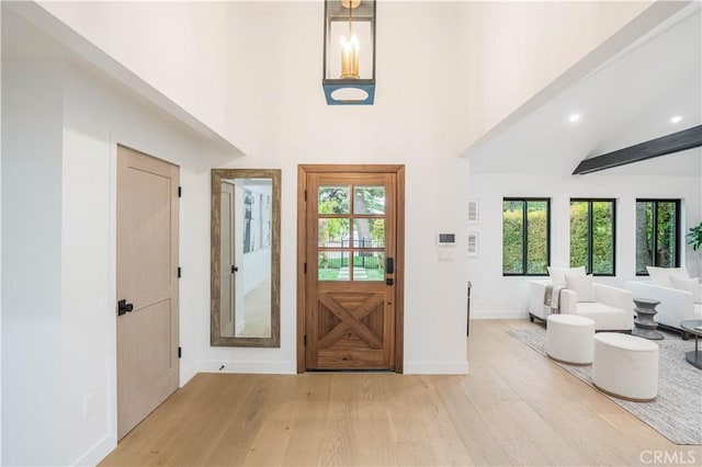 entryway with light wood-style flooring, a towering ceiling, baseboards, and recessed lighting