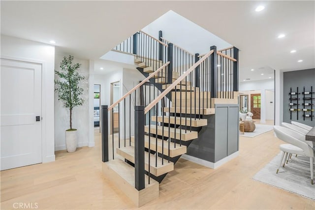 stairs with wood finished floors, recessed lighting, and baseboards