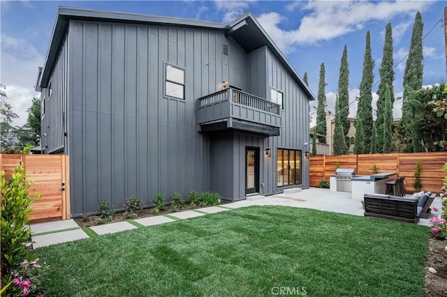 rear view of house featuring a balcony, board and batten siding, an outdoor kitchen, and a patio area
