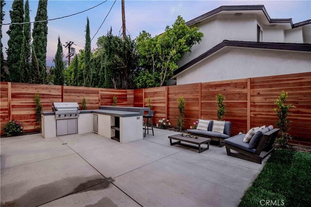 view of patio with exterior kitchen, an outdoor hangout area, a fenced backyard, and a grill