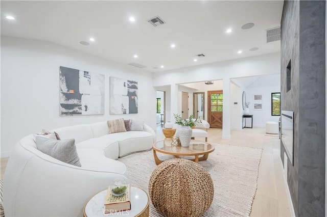 living room featuring a large fireplace, recessed lighting, and light wood finished floors