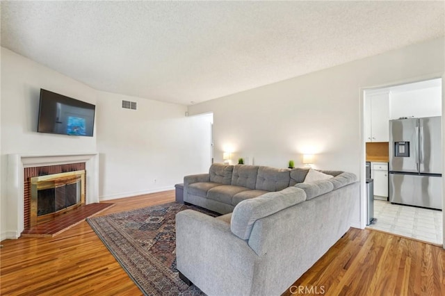 16133 Haldane St, Whittier, CA 90603 - living room with light wood-style flooring, a fireplace, a textured ceiling, and baseboards