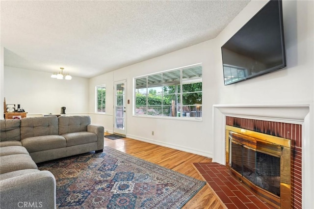 16133 Haldane St, Whittier, CA 90603 - living area with a fireplace with flush hearth, wood finished floors, a textured ceiling, a chandelier, and baseboards