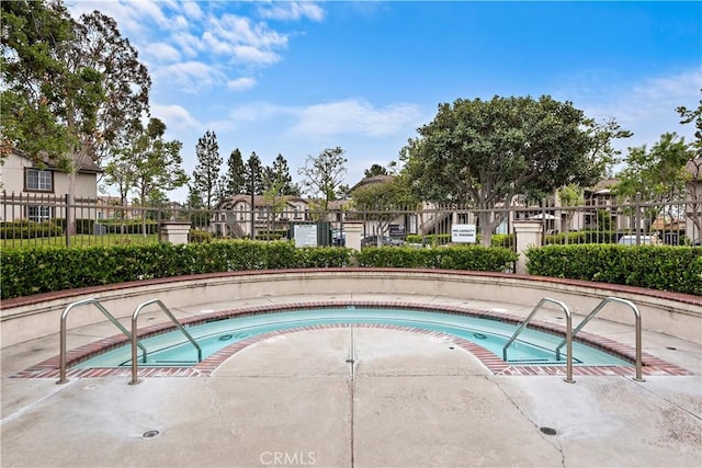 view of pool featuring fence and a community hot tub
