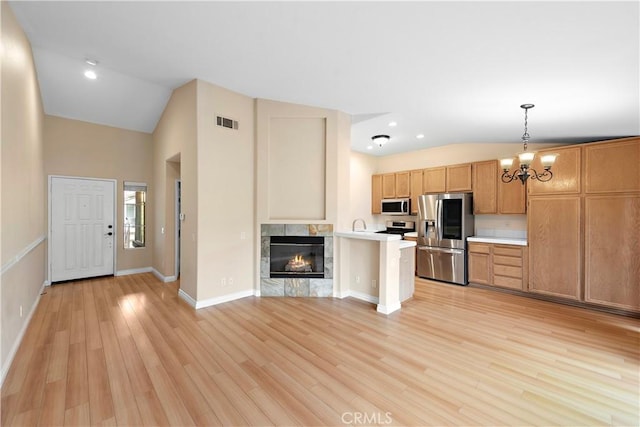 kitchen with stainless steel appliances, lofted ceiling, light countertops, open floor plan, and a chandelier