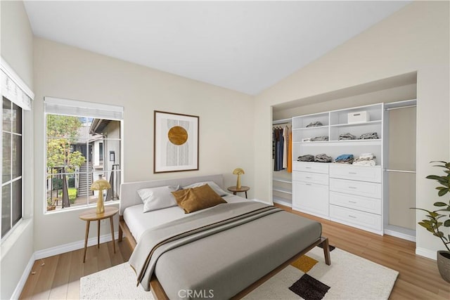 bedroom featuring light wood-style floors, baseboards, and vaulted ceiling