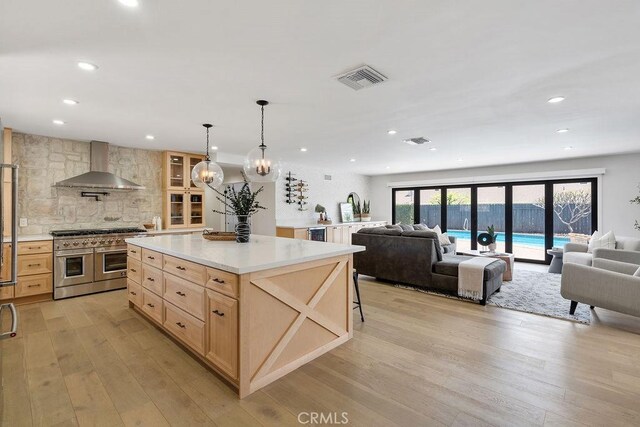 2506 E Roberta Dr, Orange, CA 92869 - kitchen featuring wall chimney range hood, range with two ovens, light brown cabinetry, open floor plan, and tasteful backsplash